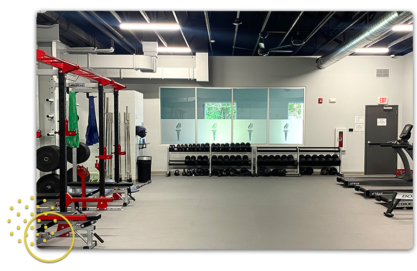 View of weight room with free weights, benches and treadmills